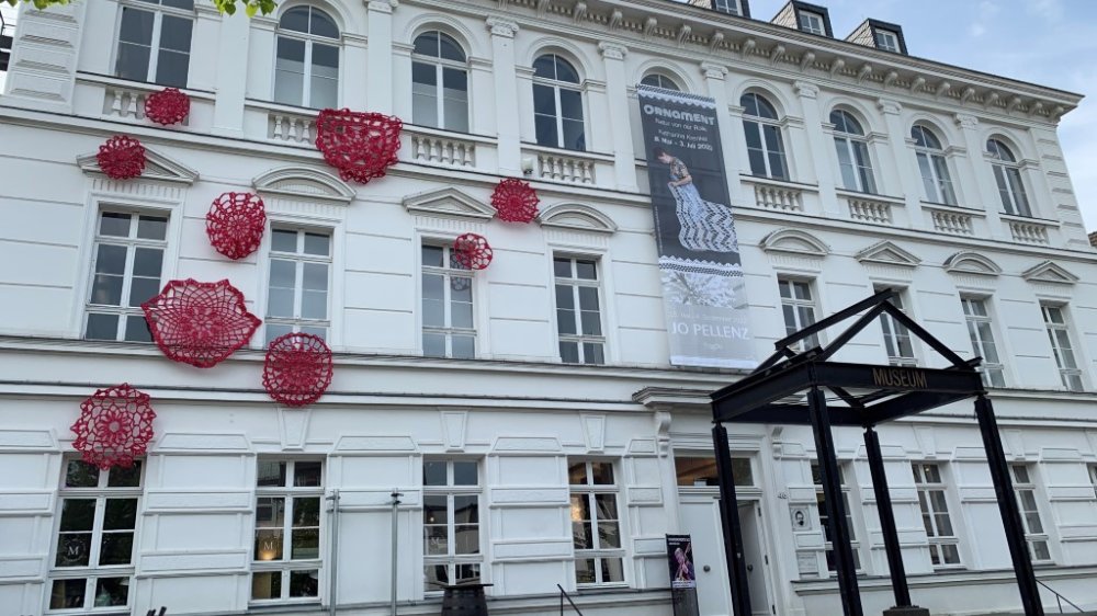 Die Außenfassade des Stadtmuseums mit roten Häkelobjekten von Katharina Krenkel.